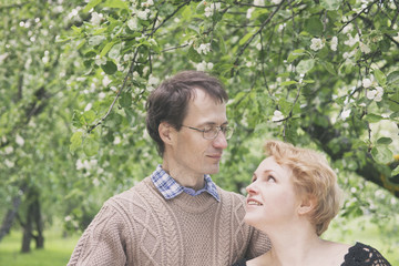 Fototapeta premium Middle aged husband and wife in blooming apple trees garden