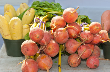 Organic, ripe, local, golden beets, yellow squash, and kale for sale at an outdoor,tropical farmers market