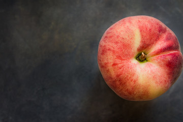 Ripe colorful red saturn peach on dark concrete background, top view, copy space, conceptual image
