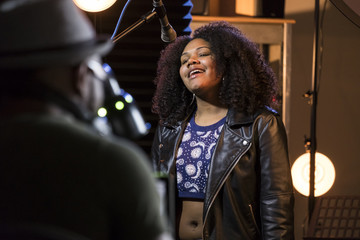 Black female vocalist working with her producer in a music studio