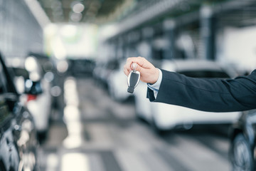 Giving a key from new car at dealership showroom