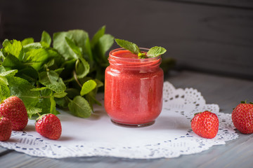 Strawberry smoothies, strawberries and a bunch of mint leaves on a dark background.
