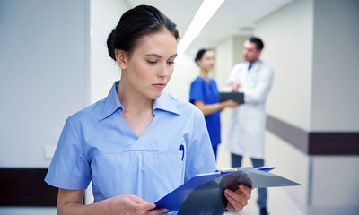 female doctor or nurse with clipboard at hospital