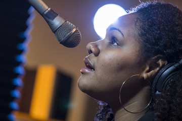 Black female singing in a recording studio, close up
