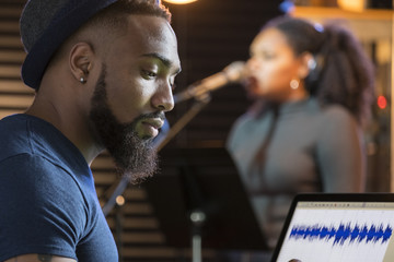 Black female vocalist working with sound engineer in a recording studio, close up shot