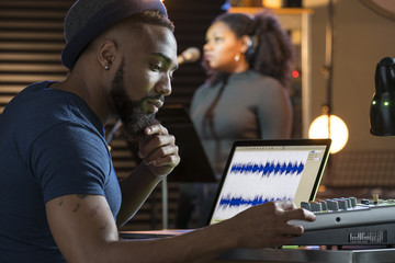 Black female vocalist working with sound engineer in a recording studio