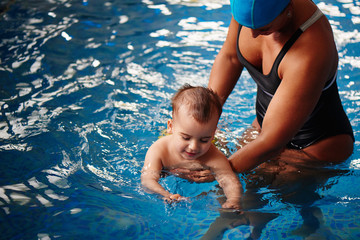 Healthy family, mother teaching baby swimming pool