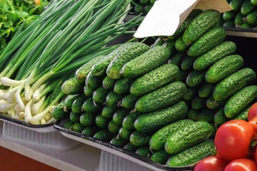 cucumbers, spring onions and fresh tomatoes on farmer's market vegetable stand