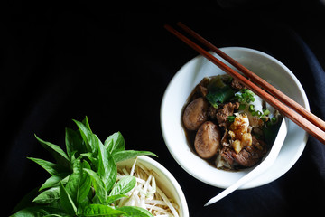 Thai noodle blood soup with pork and pork balls, delicious boat noodle, boat noodle in dark background