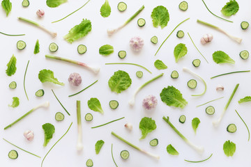Pattern of vegetables. Garlic, cucumber slices and lettuce leaves on a white background. Top view.