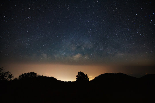 milkyway galaxy over moutain with city light and space dust in the universe