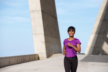 Fototapeta premium Beautiful young african american lady running outdoors.