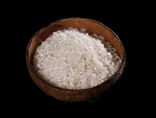 White rice in a coconut bowl isolated on black background