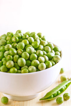 Peas in a bowl. Fresh and raw vegetable on a wooden table.