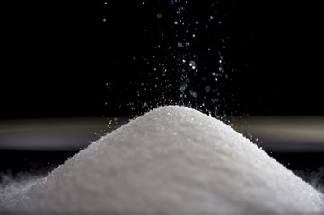 Close up shot of flowing sugar forming a pile as it falls