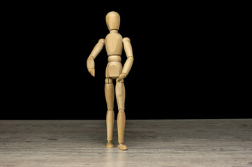 Wooden human mannequin standing on table with black background
