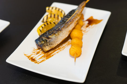 Delicious fried fish and grilled lemon as decor on white plate