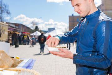 Young handsome man holding a single fresh opened oyster and squeezes out lemon