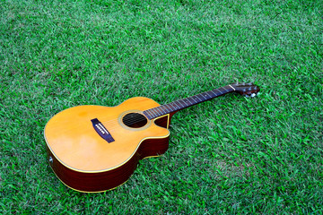  Acoustic brown guitar on green grass background.
