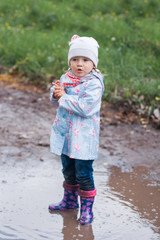 Little girl staying in the puddle and looking at the left