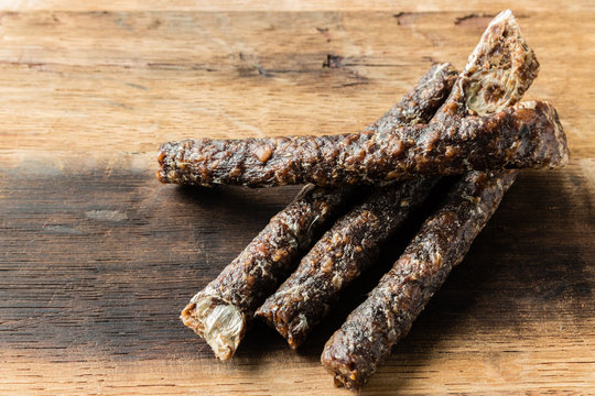 A Caucasian Hand Holding A Stick Of Droewors (dried Meat), This Is A Traditional Food Snack Found In South Africa.