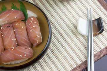 Japanese food, shushi fresh tuna, sprinkle with white sesame seeds in a wooden dish on a mat.