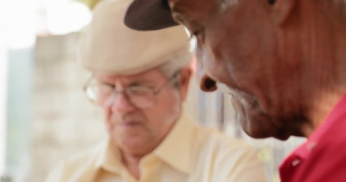 Senior Latino Man Playing Domino With Old Friends