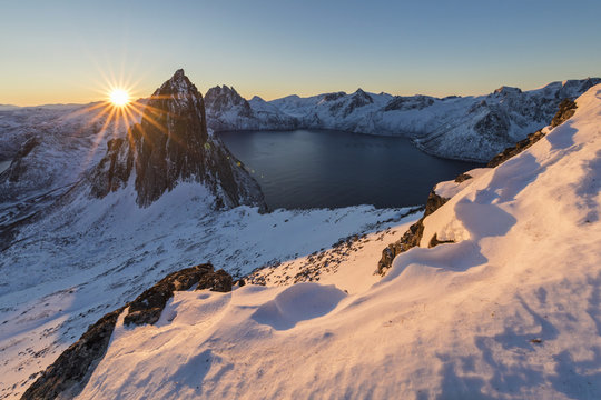 First lights of sunrise on Mount Segla and Mefjorden framed by the frozen sea seen from peak Hesten Senja Troms&oslash; Norway Europe