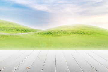 Wood table top on mound slope green grass natural background in morning time.