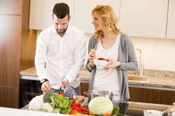 Man helping his girlfriend cooking in modern kitchen
