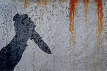 Human hand with killing knife silhouette in shadow on bloody concrete wall and blood background....