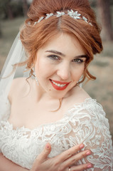 Beautiful bride glows with happiness. Happy bride is smiling and is looking at the camera. Red hair bride. Lace wedding dress.