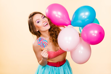 Woman holds lollipop candy and balloons