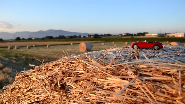 Toy car on a round bale at the sunset