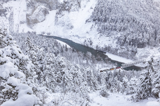The Red Train passes in the gorge despite heavy snow. Rhein Gorge(Ruinaulta), Flims, Imboden, Graubunden, Switzerland, Europe