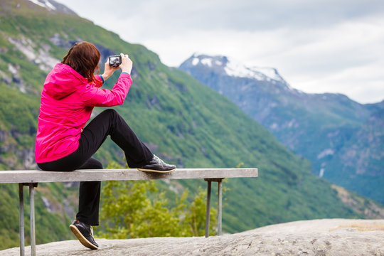 Tourist with camera looking at scenic view in mountains Norway