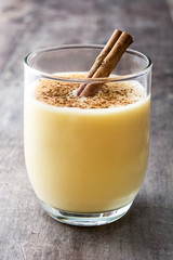 Homemade eggnog with cinnamon on wooden table. Typical Christmas dessert.
