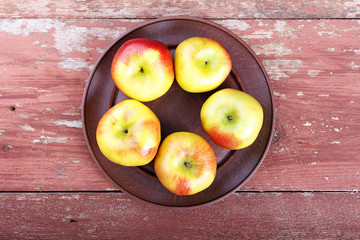 ripe in a dish apples on a wooden table, summer harvest, healthy eating.