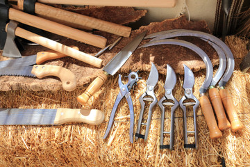 Agricultural tools exposed on a bale of hay - obrazy, fototapety, plakaty