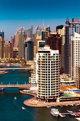 Naklejka premium Amazing colorful dubai marina skyline with water canal and expensive yachts during sunny day, Dubai, United Arab Emirates.