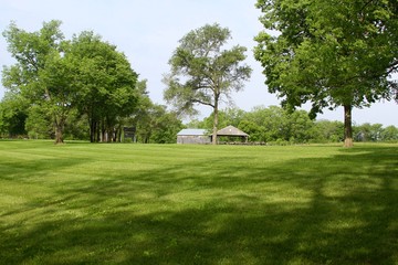 The parks grass landscape with the barn and buildings in background.