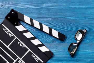 Attributes of film director. Movie clapperboard and sunglasses on blue wooden table background top view