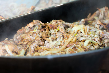 Große Pfanne mit gebratenem Gyros und Zwiebeln  in Bratendunst