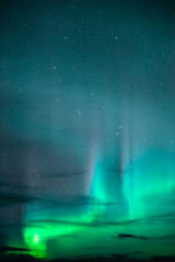 The Aurora Borealis emerges through clouds remote Alaska
