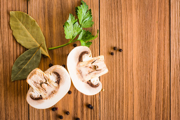 Halved fresh button champignons, bay leaf and parsley on a wooden table. Top view
