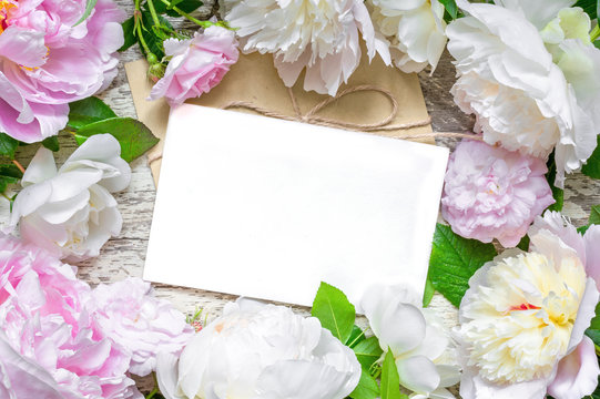 blank greeting card and envelope in frame of pink and white peonies and roses