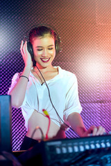 Young asian woman DJ listening to the music in headphones for party, party concept