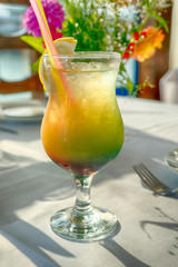 Alcohol cocktail glass layered with lemon and with two tubes worth on the table