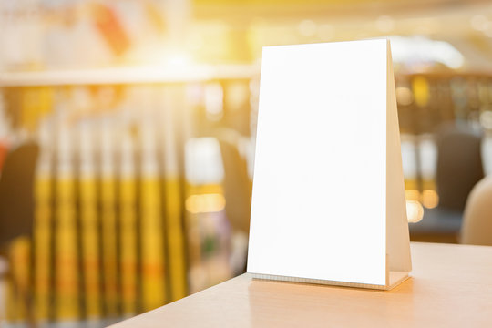 Mock up Menu frame on Table in Bar restaurant ,Stand for booklets with white sheets of paper acrylic tent card on cafeteria blurred background