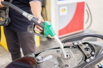 hand fuel nozzle in pouring to motorcycle at gas station,selective focus,vintage color